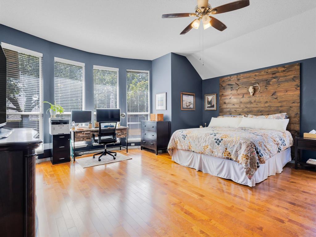 Expansive room featuring rich wood-finish flooring, a vaulted ceiling, and a ceiling fan with integrated lighting