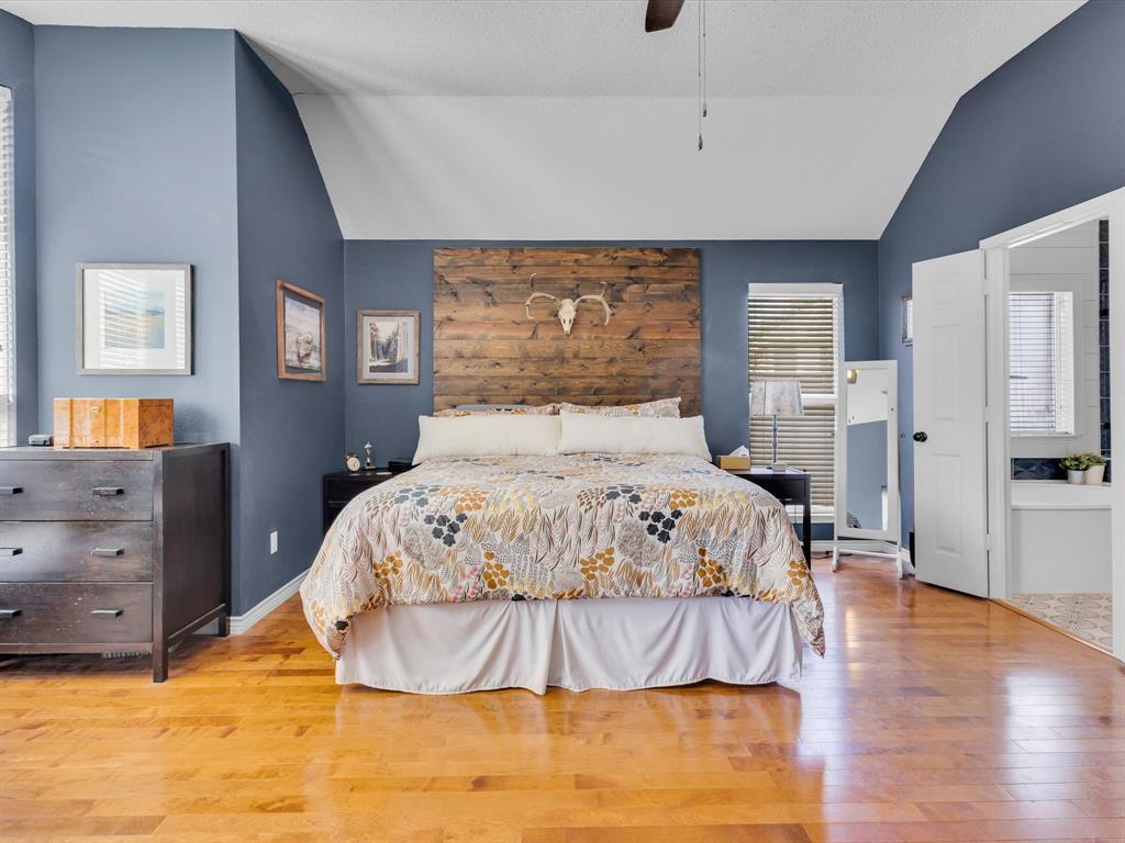 Spacious bedroom featuring vaulted ceilings, wood-finish flooring, and a unique wood plank accent wall