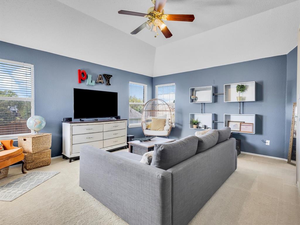 Vaulted ceiling room featuring multiple windows, a ceiling fan with integrated lighting, and carpet flooring