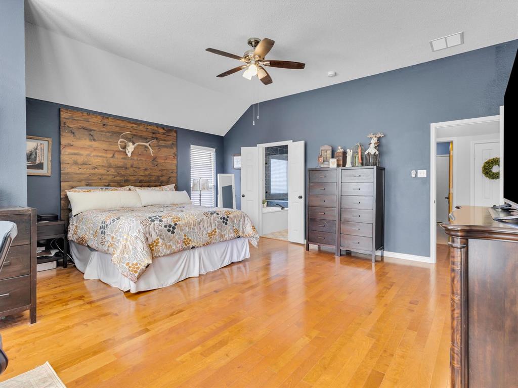 Spacious room featuring vaulted ceilings, wood-finish flooring, and a ceiling fan