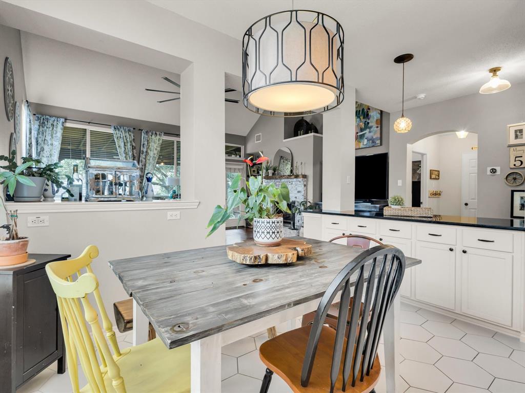 Kitchen dining area featuring a geometric pendant light fixture, white hexagonal floor tiling, and a pass-through window opening
