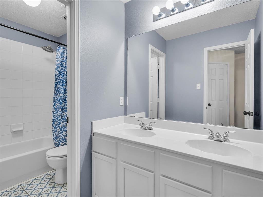 Bathroom featuring a dual vanity with white cabinetry, white countertops, and chrome fixtures