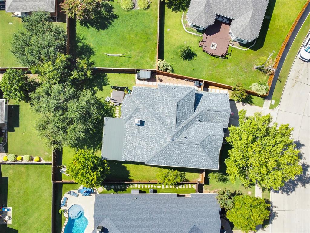 Aerial perspective of a property featuring a multi-gabled roofline, a private backyard with established trees, and a concrete patio space