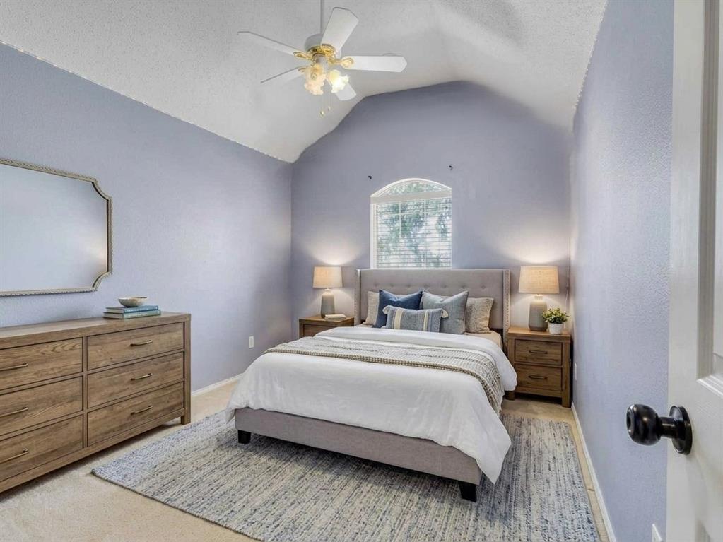 Room featuring a vaulted ceiling with a ceiling fan, an arched window with blinds, and light-colored walls. This bedroom photo is virtually staged.