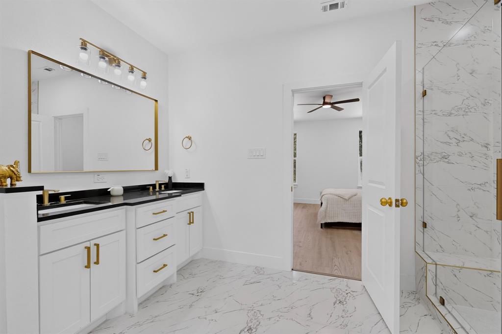 Bathroom featuring a double vanity with black countertops and white cabinetry