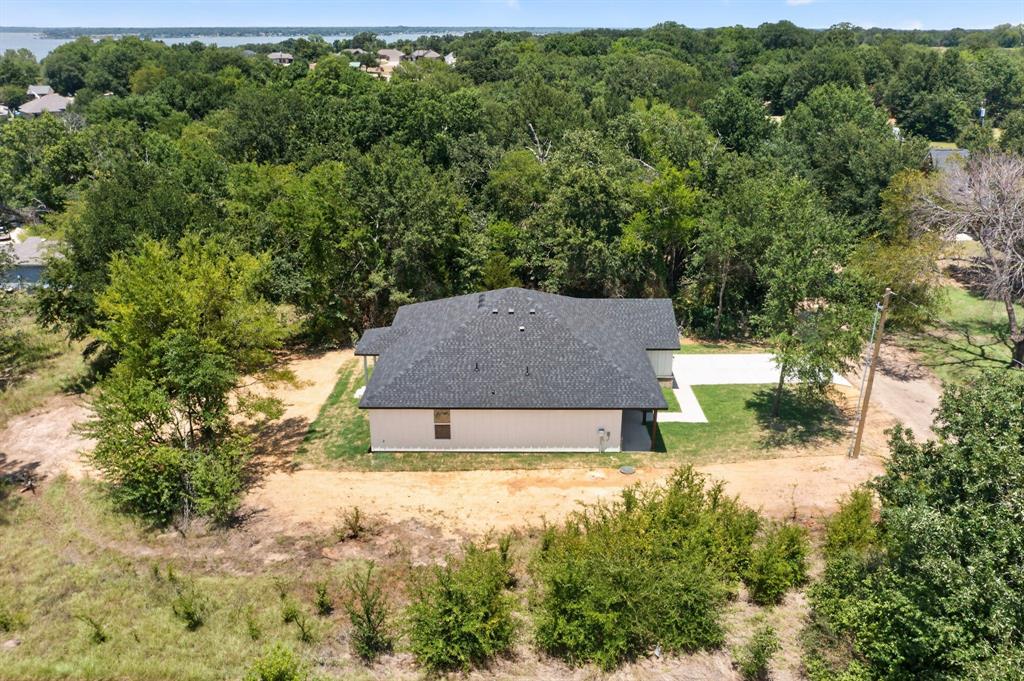 New construction single-story home with light-colored siding and a dark shingled roof