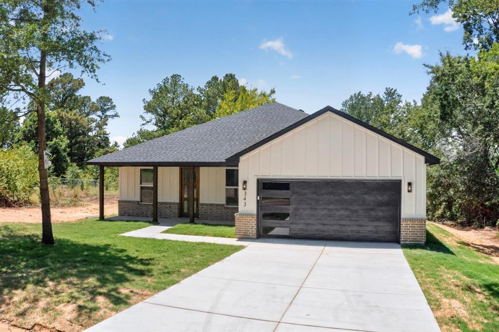 Contemporary exterior featuring light vertical siding, a dark asphalt shingle roof, and a modern garage door with frosted glass panels