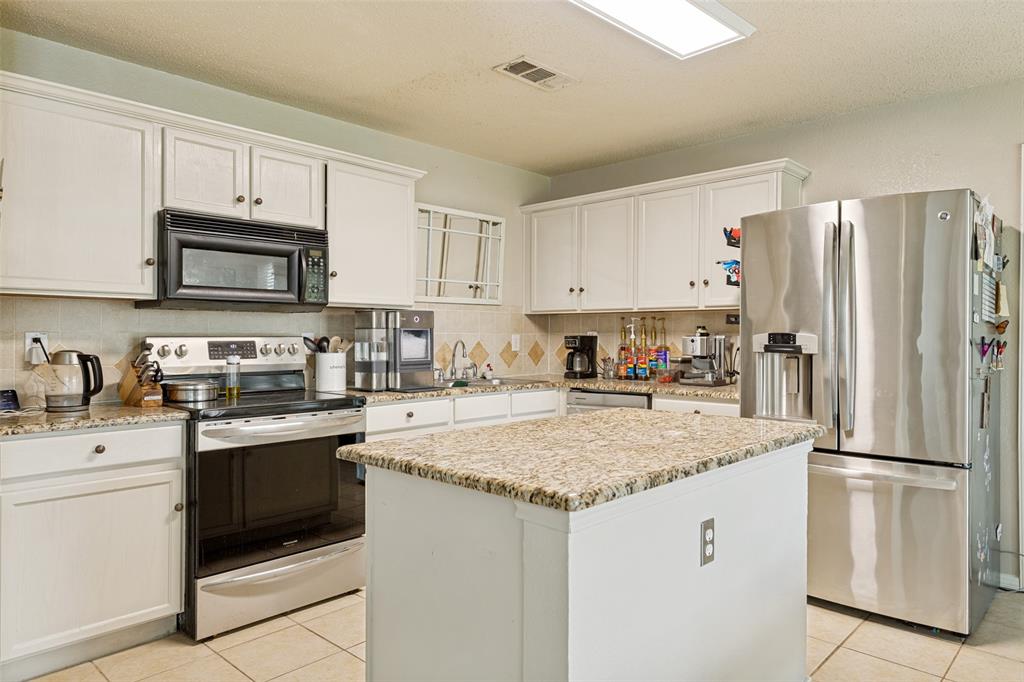 Kitchen featuring white cabinetry, light granite countertops, and stainless steel appliances