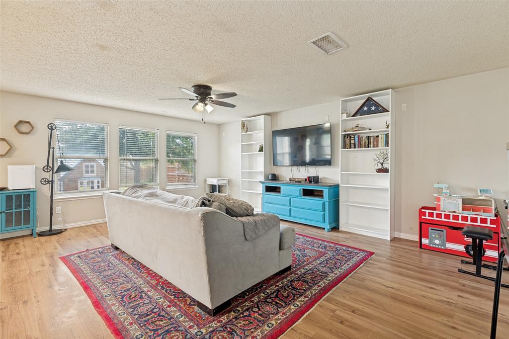 Living area with wood-finish flooring, multiple windows, built-in shelving, a ceiling fan, and recessed lighting