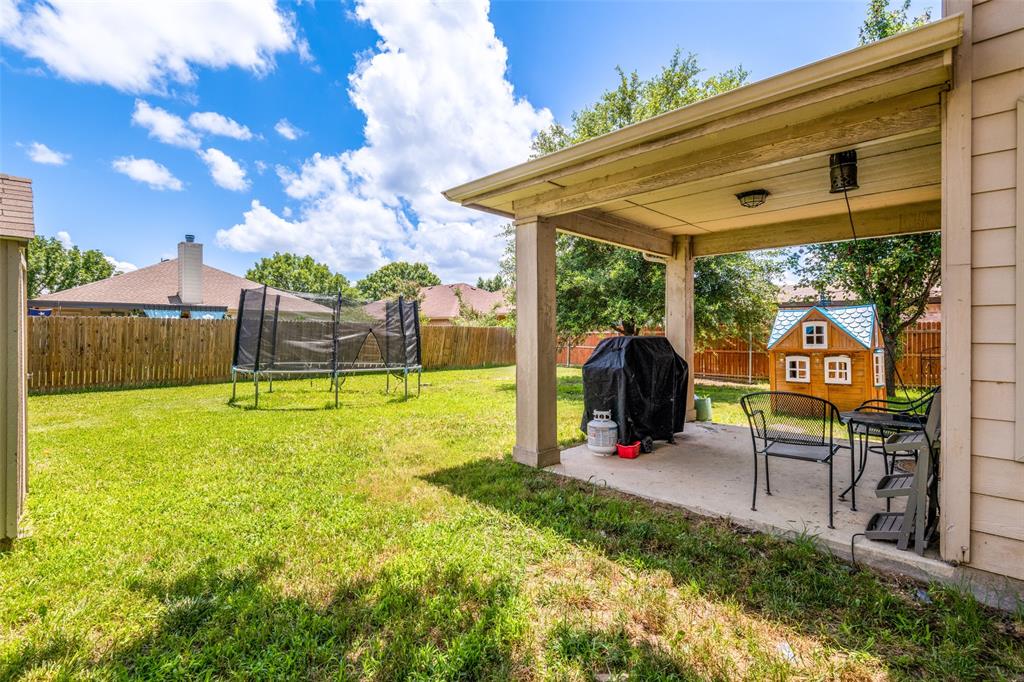 Expansive backyard featuring a concrete patio, covered outdoor living space, and a wood privacy fence