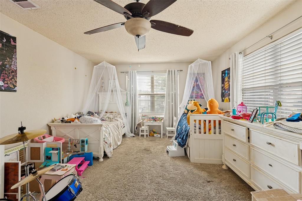 Carpeted room featuring multiple windows with blinds, a ceiling fan, and painted walls