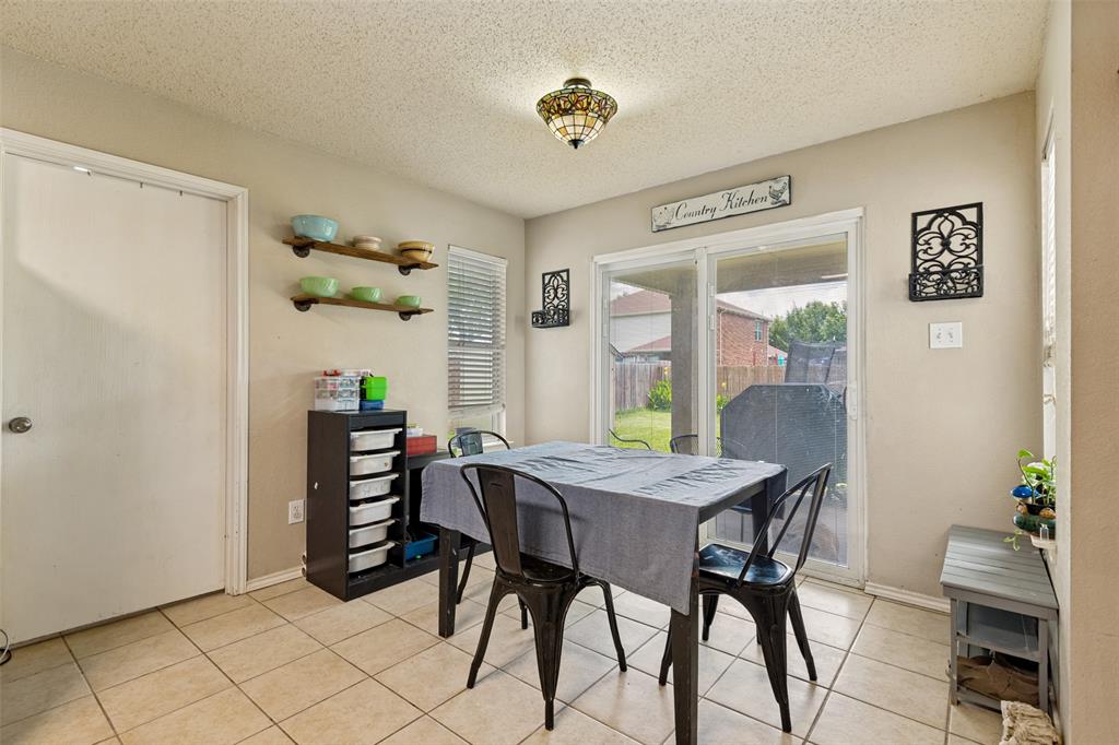 Bright dining area featuring tile flooring, sliding glass doors, built-in shelving, a ceiling-mounted light fixture, and neutral wall tones