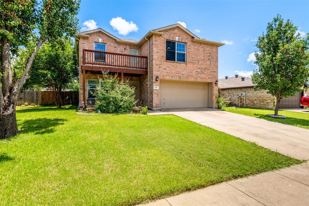 Brick exterior residence featuring a second-story balcony with wood railing, an attached garage, and a concrete driveway