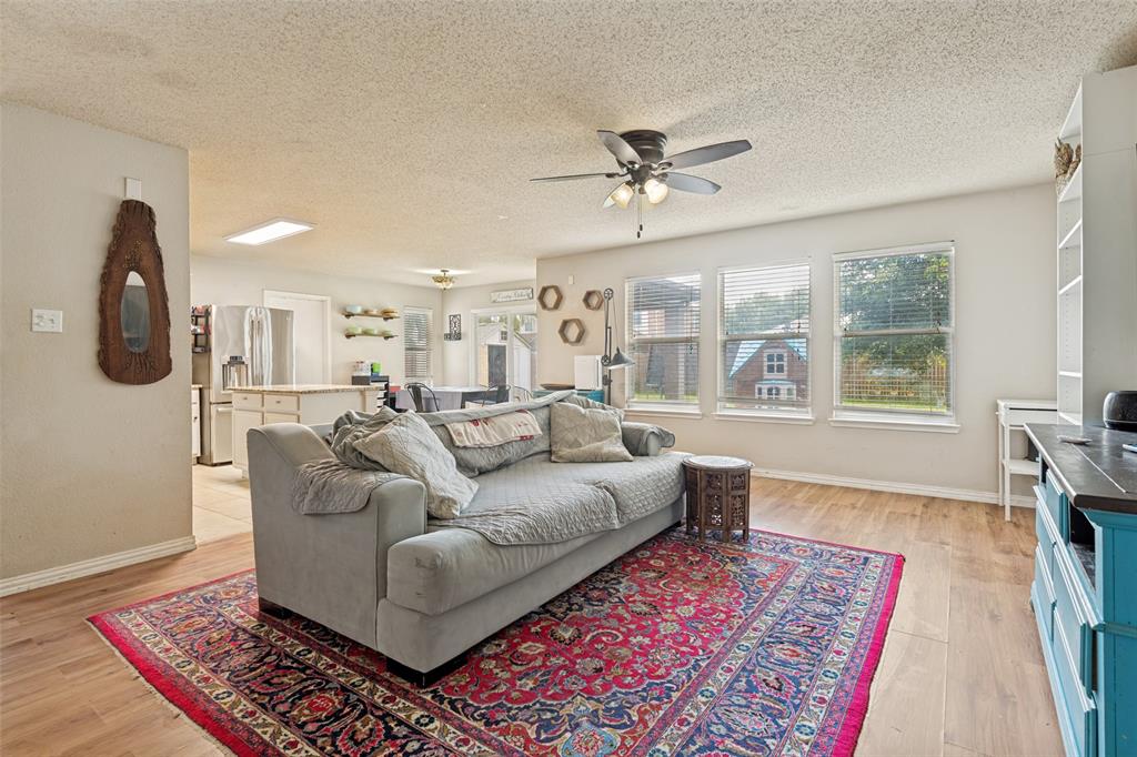 Open-concept living area featuring wood-finish flooring, multiple windows providing ample natural light, a ceiling fan with integrated lighting, and recessed ceiling lighting