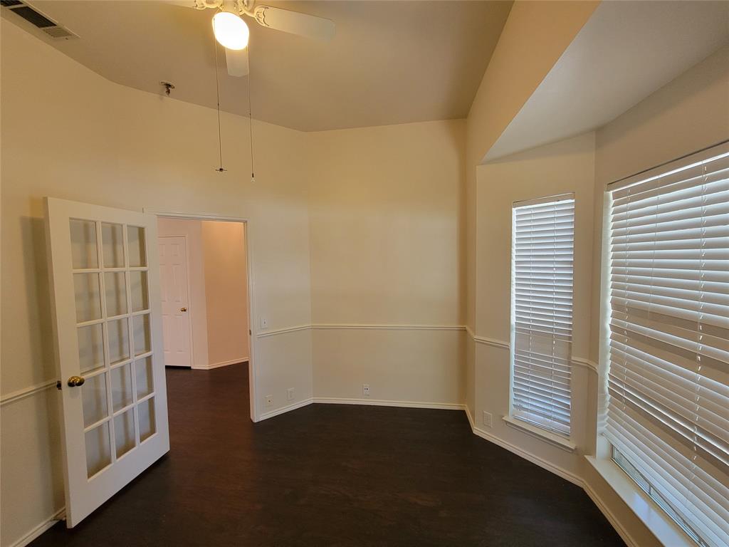 Office with bay window, glass door, and dark wood-style floors, ceiling fan, and lofted ceiling