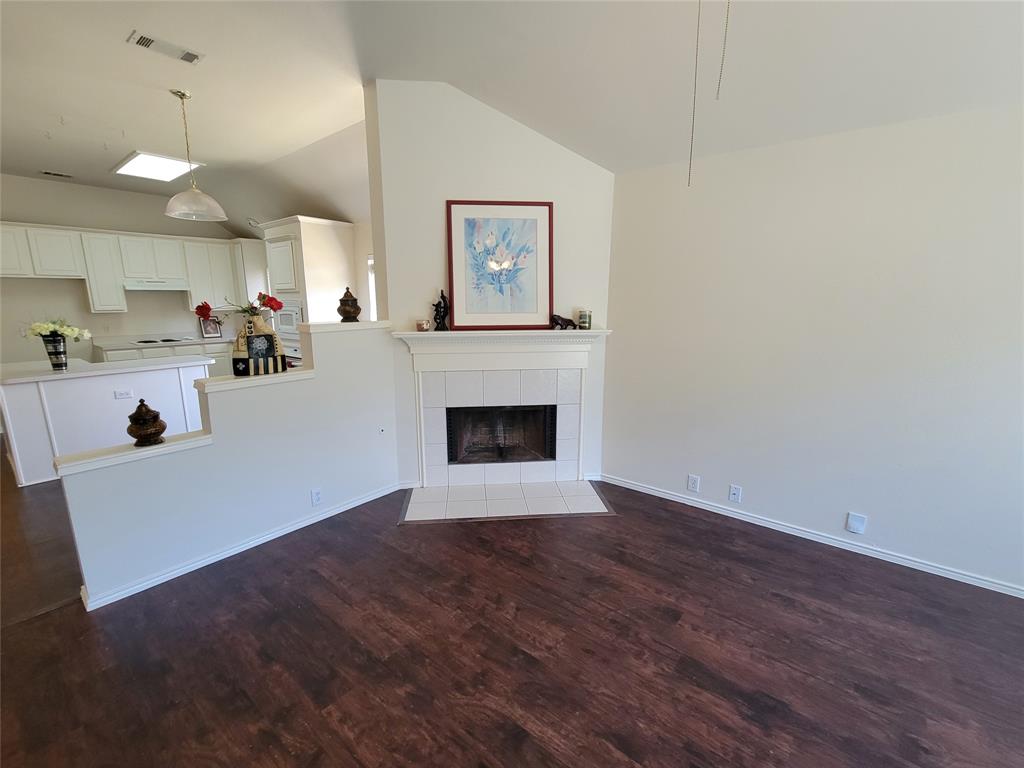 Living room with a fireplace, dark wood-style floors, ceiling fan, and lofted ceiling