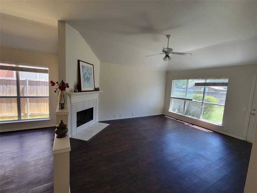 Living room with a fireplace, dark wood-style floors, ceiling fan, and lofted ceiling