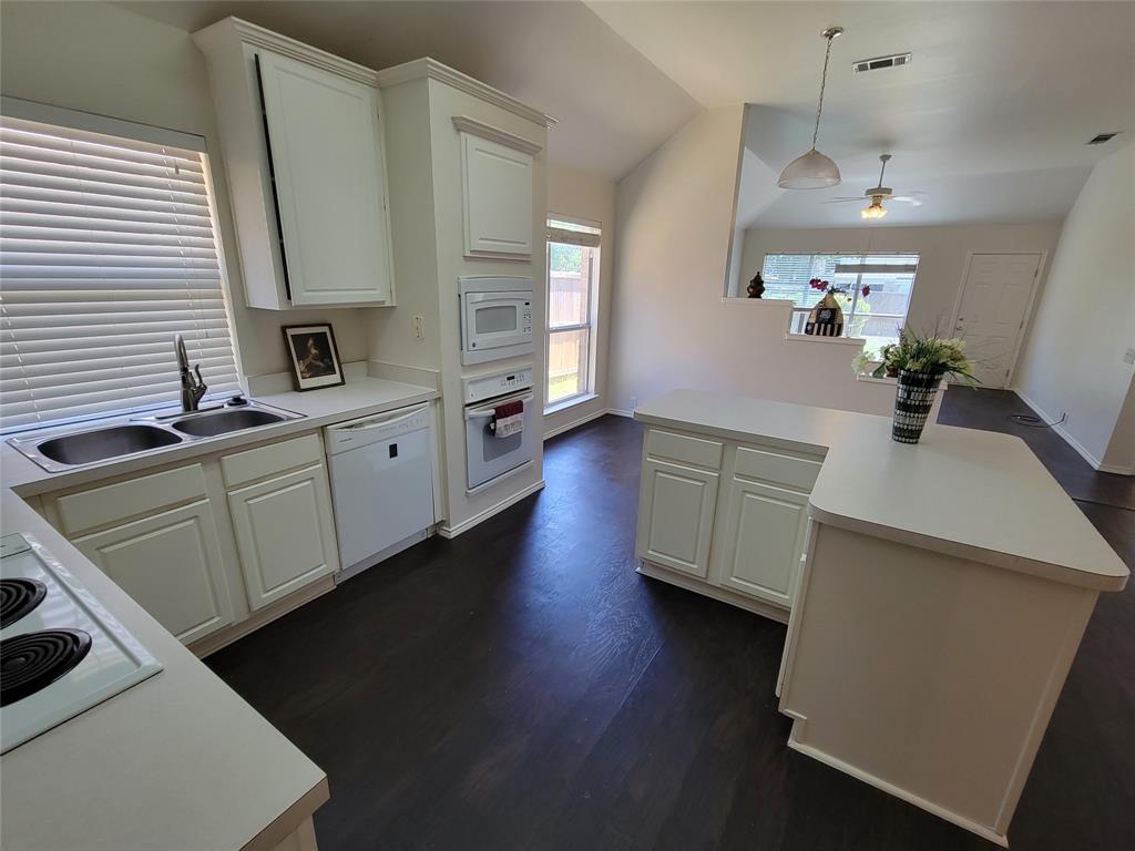 Kitchen with ceiling fan, white appliances, sink, vaulted ceiling, and dark wood-style floors