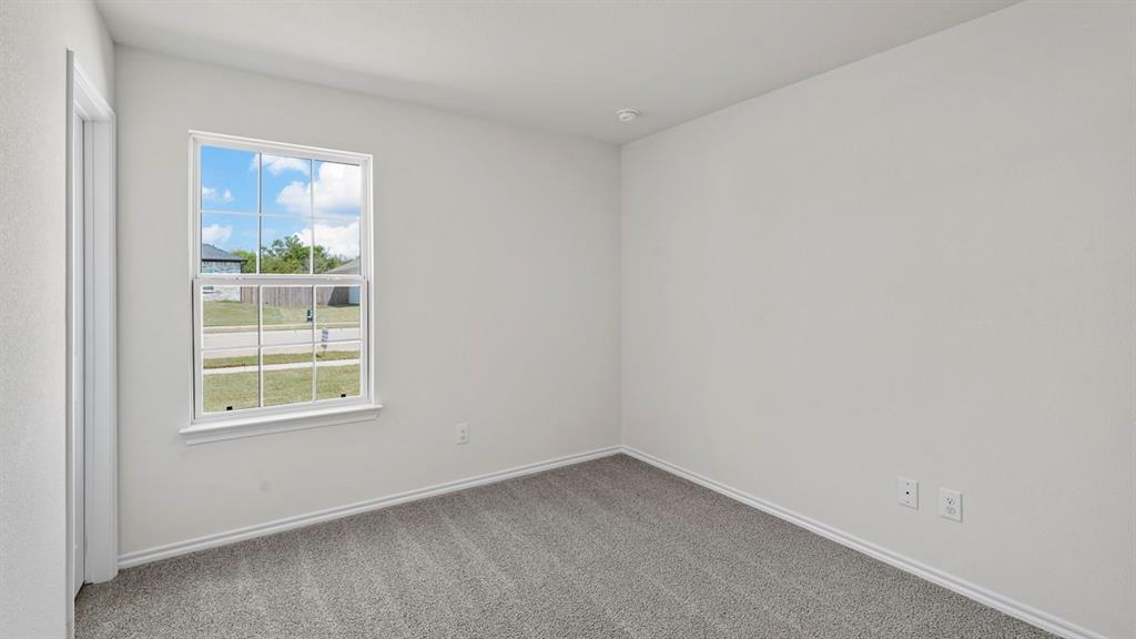 Bright room featuring light gray carpeting, neutral wall finishes, and a framed window providing exterior visibility