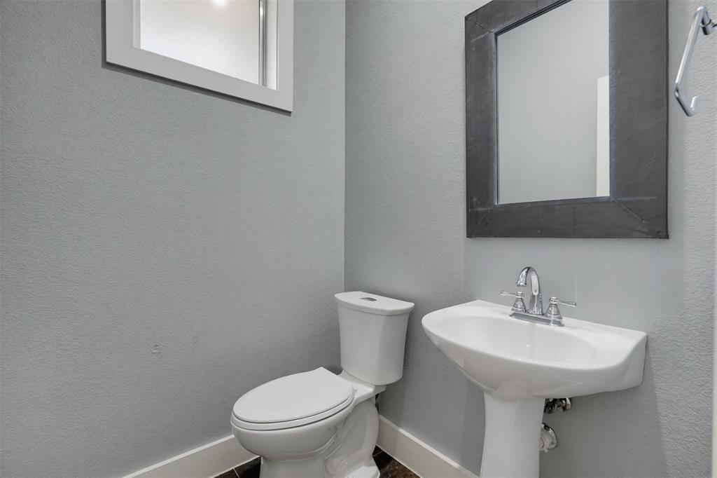 Pedestal sink with chrome faucet, white toilet, and dark framed mirror