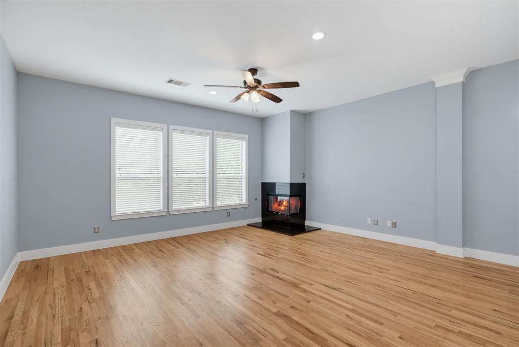 Living area featuring a corner fireplace with a dark surround, light wood-finish flooring, three windows with blinds, a ceiling fan, and recessed lighting