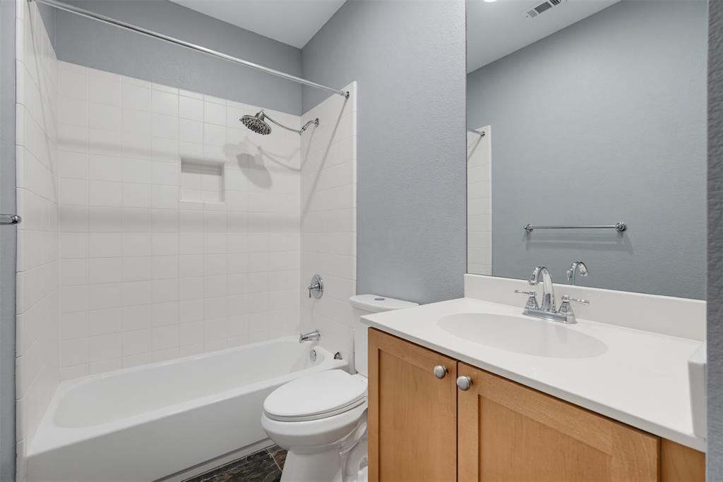 Full bathroom featuring a single vanity with wood-finish cabinetry and a light-toned countertop