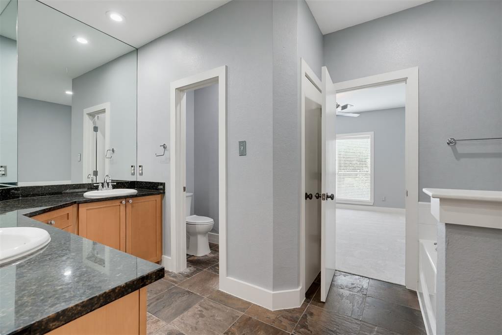 Bathroom featuring a double vanity with stone countertops, wood cabinetry, and extensive wall mirror