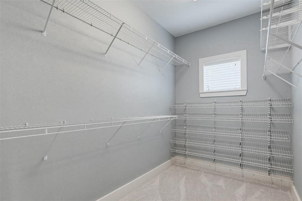 Walk-in closet featuring light gray walls, white wire shelving, white baseboards, and carpet flooring