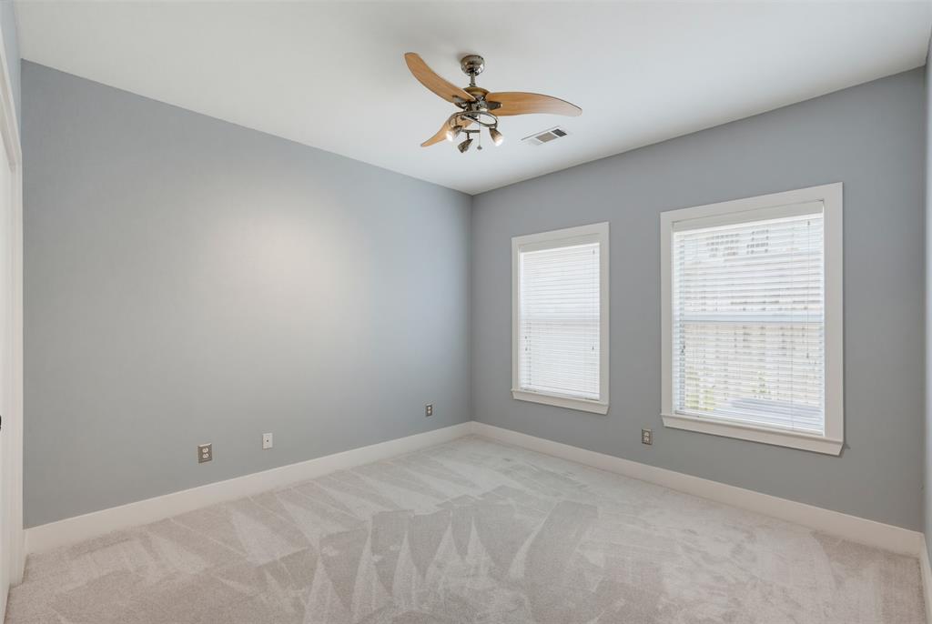 Carpeted room with light grey walls, two windows featuring white blinds, and a ceiling fan with integrated lighting