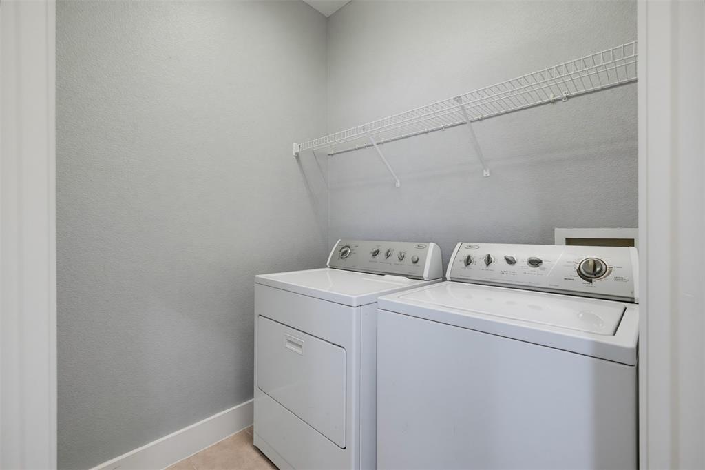 Dedicated laundry area featuring a white washer and dryer set, overhead wire shelving, light gray wall finish, and neutral flooring