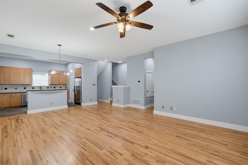 Living area featuring wood-finish flooring, a contemporary fireplace with a black stone surround and hearth, a wood mantel, recessed lighting, and a ceiling fan