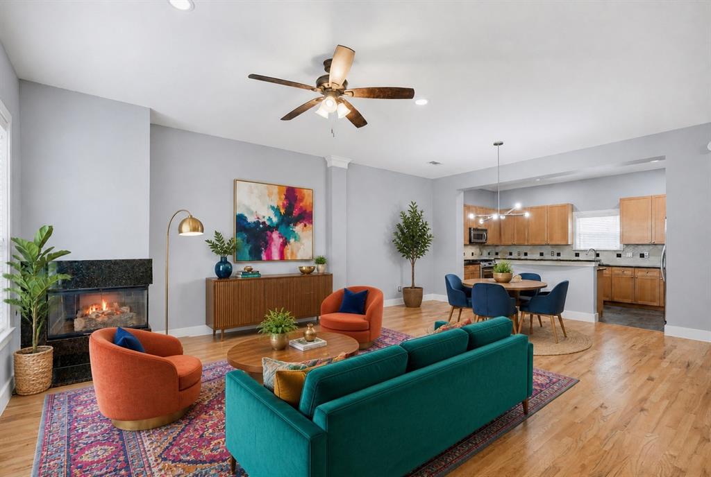 Living area with a built-in fireplace featuring a dark stone surround, wood-finish flooring, recessed lighting, and a ceiling fan