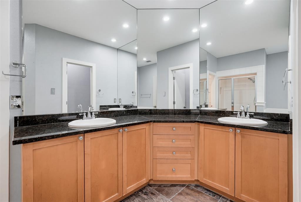 Bathroom vanity featuring dual under-mount sinks set into a dark granite countertop