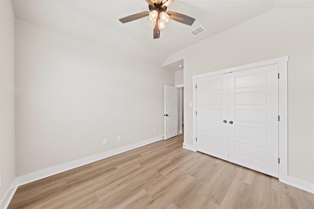 Spacious room featuring wood-finish flooring, white baseboards, and a modern ceiling fan with integrated lighting