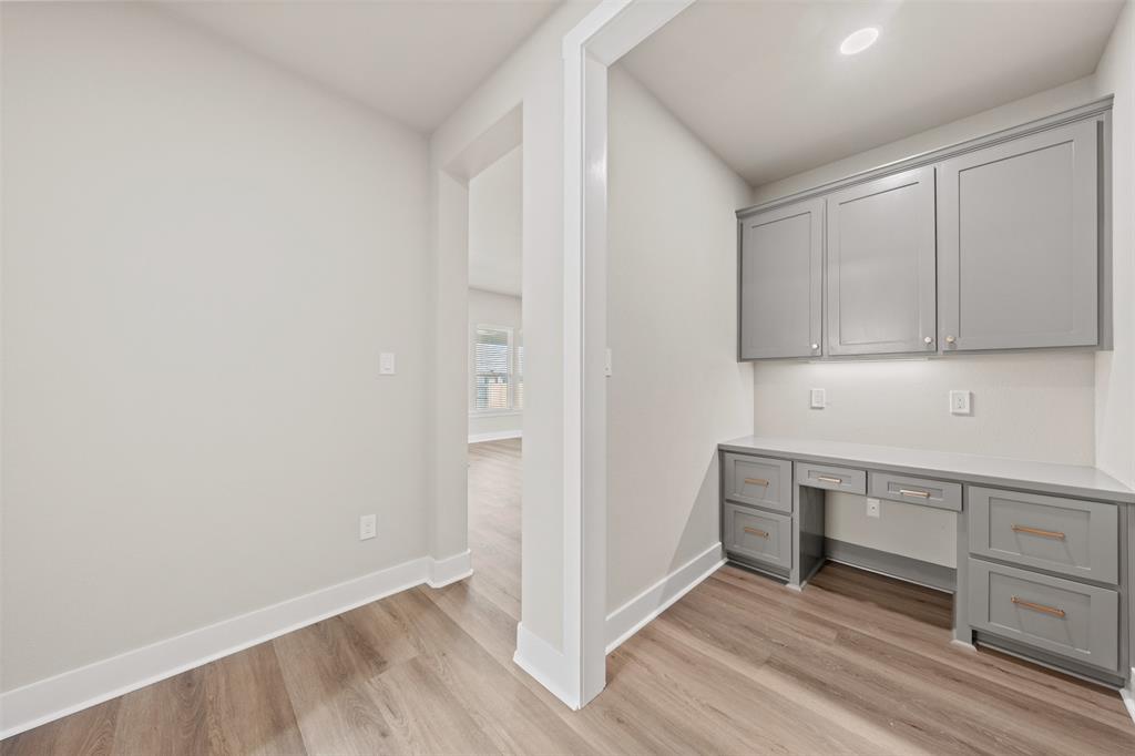 Built-in desk area featuring grey cabinetry, a light-toned countertop, and under-cabinet lighting