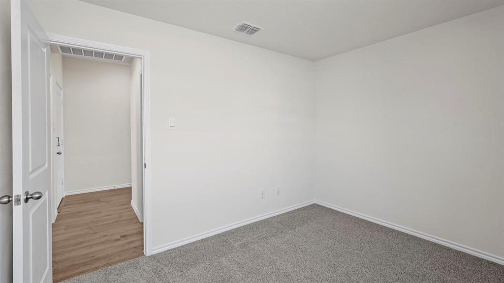 Room featuring light gray carpeting, white painted walls, white trim, and a white interior door with polished nickel hardware