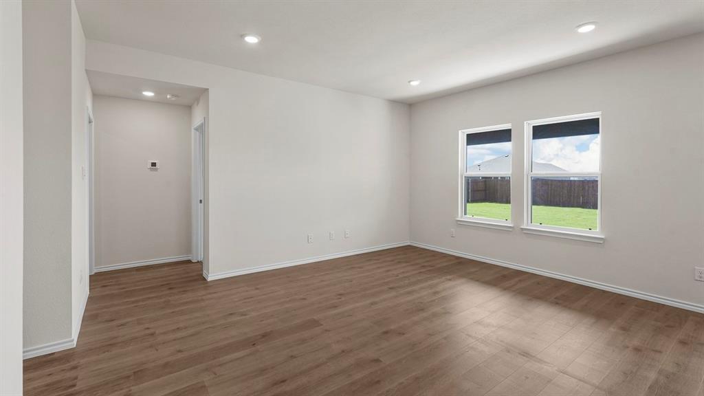 Spacious room featuring wood-finish flooring, recessed lighting, and two double-hung windows with roller shades