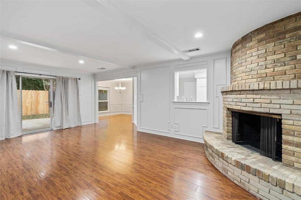 Living room with wood burning fireplace and sliding glass doors that lead out to fenced in side yard and patio.