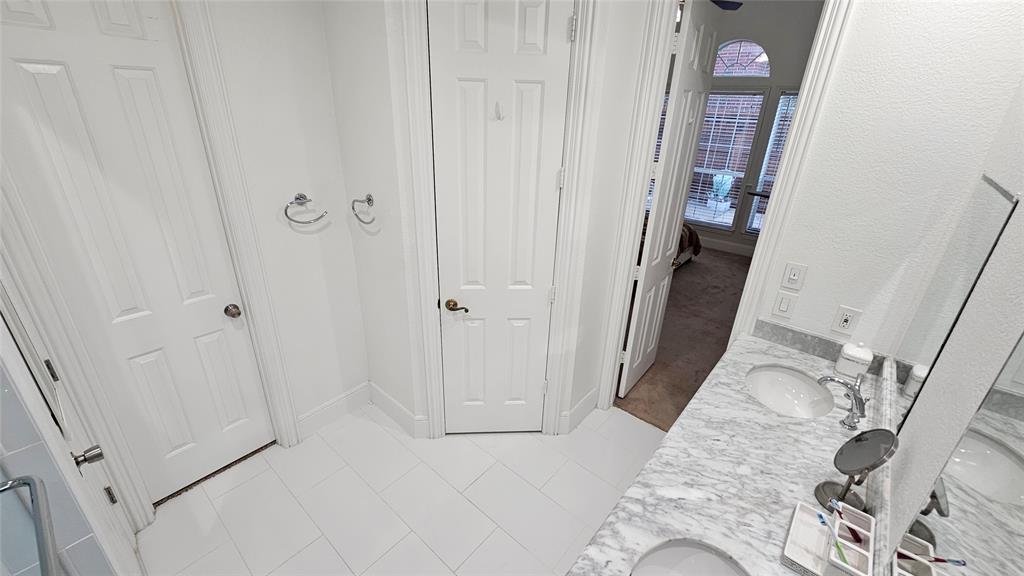 Bathroom featuring a double vanity with stone countertops, undermount sinks, and chrome fixtures