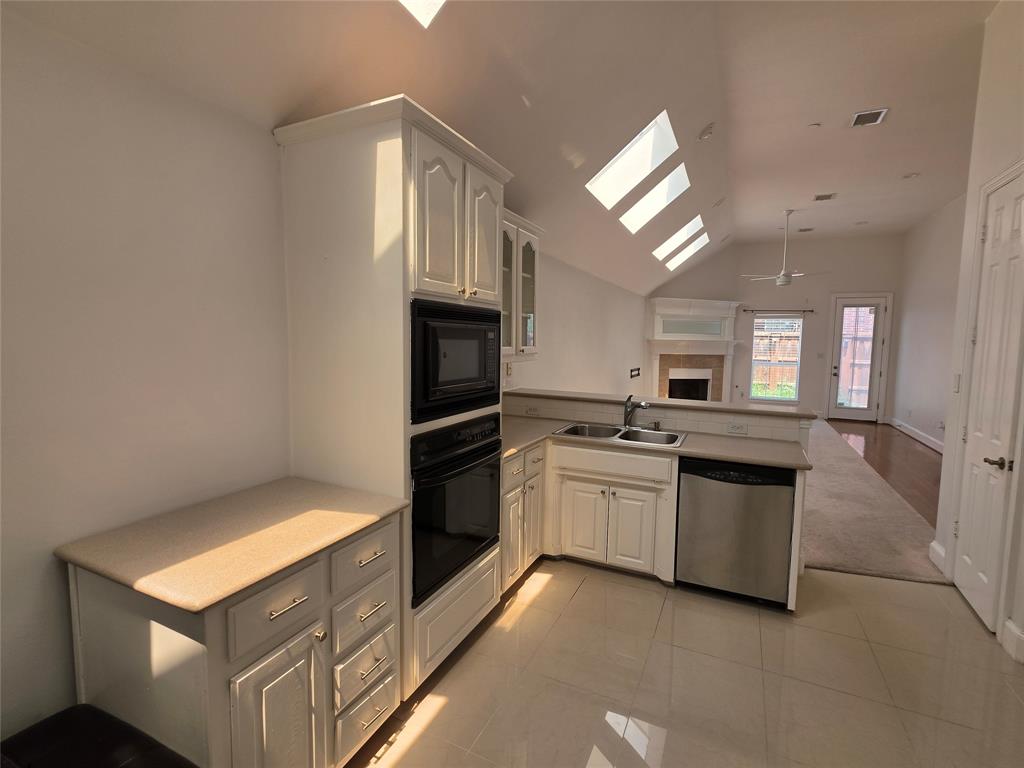 Kitchen featuring white cabinetry, built-in microwave and oven, a stainless steel dishwasher, and a double basin sink