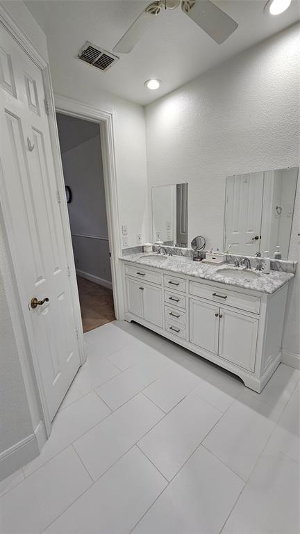 Dual vanity featuring white cabinetry and a light-colored stone countertop with integrated sinks