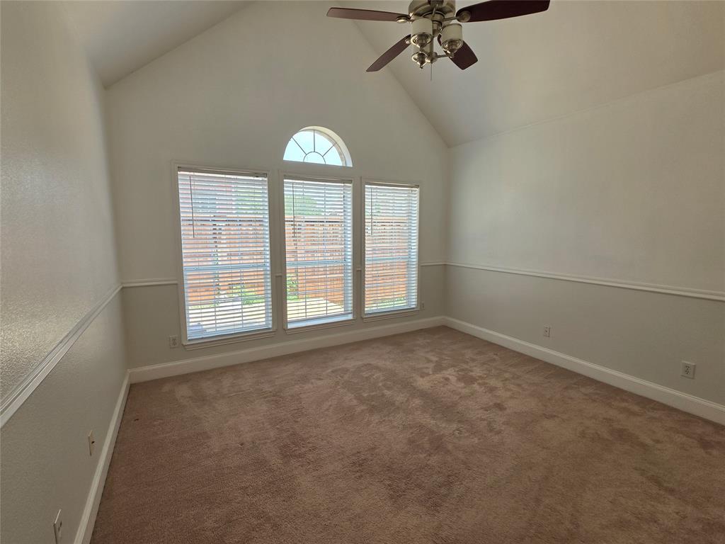 Vaulted ceiling room featuring three large windows with blinds and an arched transom window