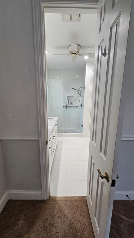Bathroom featuring a white tiled floor, a glass-enclosed shower, and a vanity with a light-colored countertop