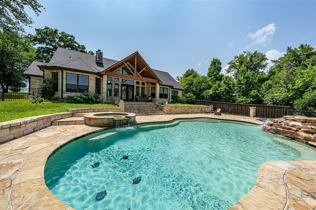 Expansive outdoor living area featuring a freeform swimming pool with a stone waterfall feature and integrated spa