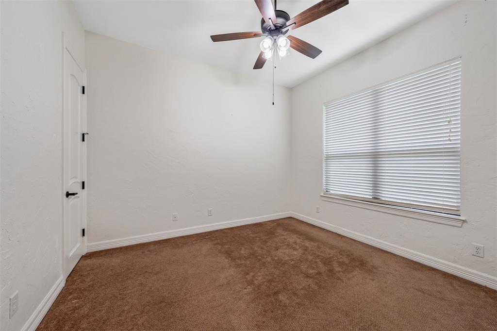 Interior room featuring neutral wall paint, brown carpeting, a window with horizontal blinds, and a ceiling fan with integrated lighting