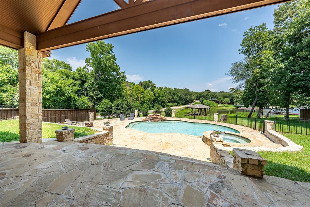 Covered outdoor patio with flagstone flooring, stone columns, and a wood-beam ceiling