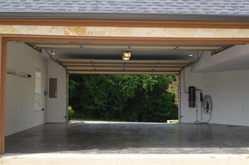 drive through garage -coated concrete floor, an overhead garage door, built-in central vacuum system, recessed lighting, and a window with blinds