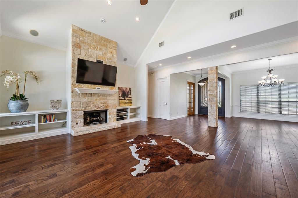 Spacious interior featuring wood-finish flooring, a stone-clad fireplace with built-in shelving, vaulted ceilings, and recessed lighting