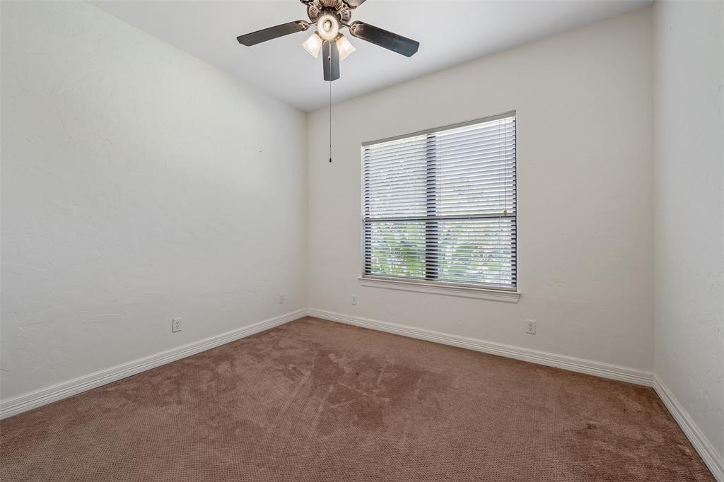 Carpeted room featuring a ceiling fan with integrated lighting, a window with horizontal blinds, textured walls, and white baseboards