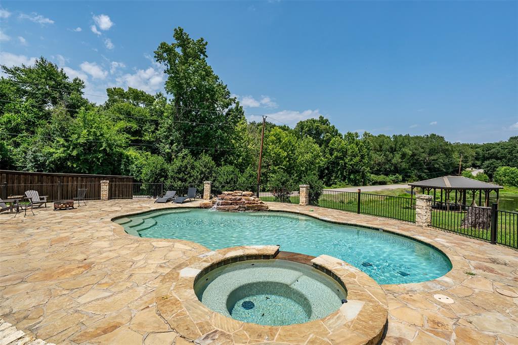 Freeform swimming pool with integrated spa and stone waterfall feature